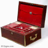SB454: Mahogany and brass bound sewing box circa 1820. This is a most unusual early sewing box, both strong and robust. The high quality of the structure suggests that it was made to withstand travel as well as sit in elegant drawing rooms. The mahogany is edged in squared brass all around and bears flat-folding side handles. The original interior is lined in red textured leather. The tray is in keeping with the exterior and is structured for strength. The ‘envelope’ is most unusual and opens with a silver catch. Some bending on bottom brass suggesting that the box did travel! Working Bramah lock and key. Enlarge Picture